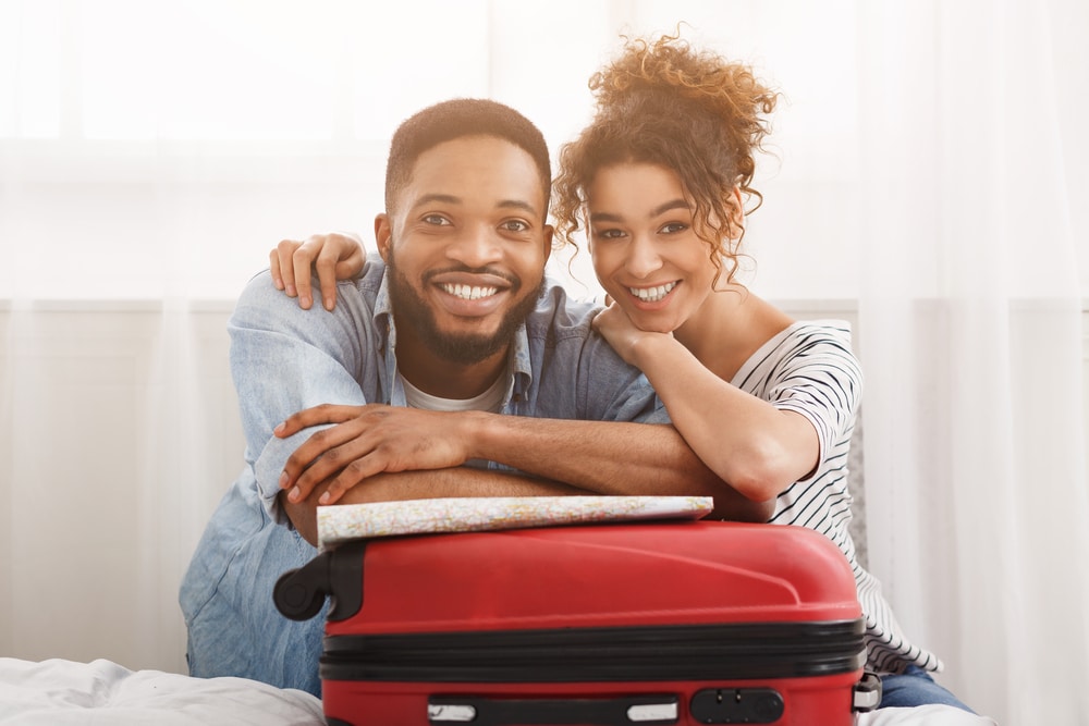 Happy couple leaning on suitcase, preparing for vacation