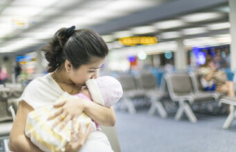 Flying With a Baby For the First Time? Here’s What You Need to Know Mum holding a baby at the airport