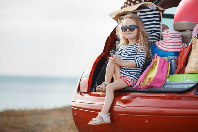 Little girl seating on the boot of a car.