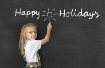 How to Keep Your Kids Entertained During School Holidays Female student in front of a blackboard that says "Happy Holidays."