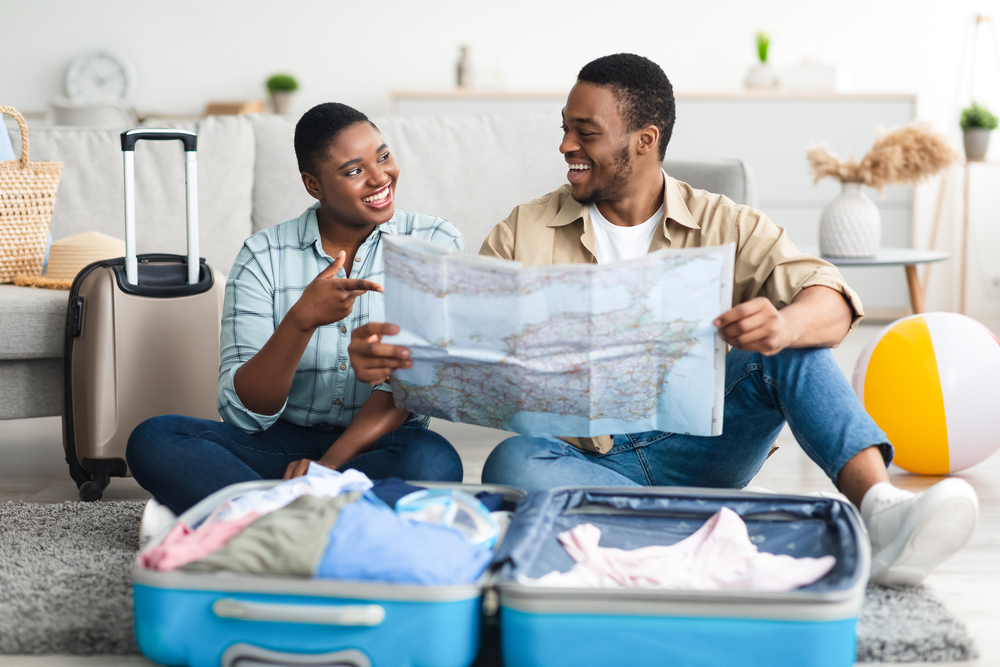 Family Planning Vacation Holding Map Sitting Near Suitcase Indoor